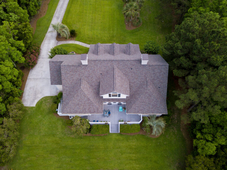 Aerial view of large home with new roof on beautiful property.